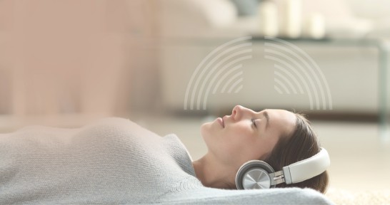 Frau liegt entspannt mit Kopfhörern auf dem Rücken